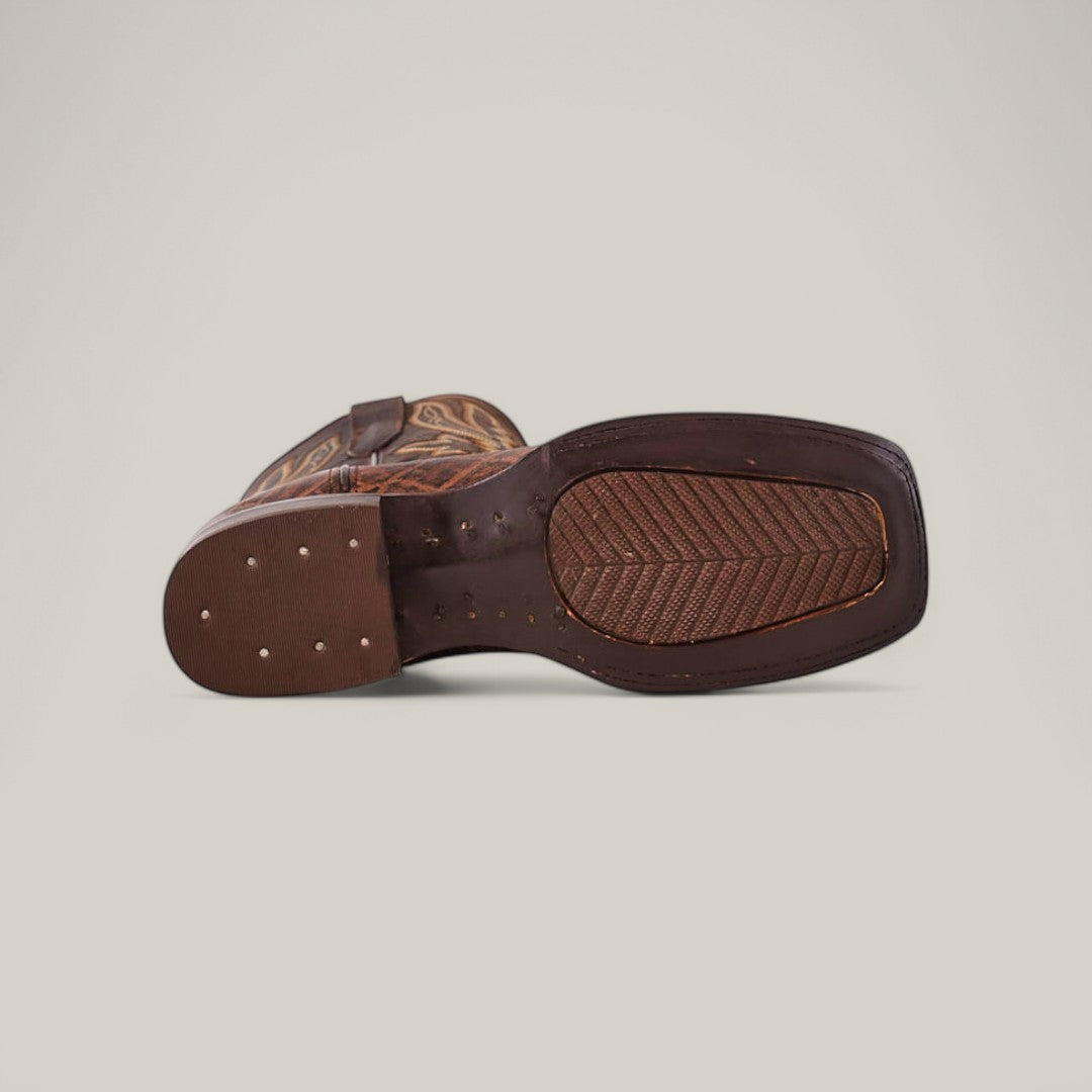 The image highlights the sole of the Mamut Grimm Brown - Square Toe boot, crafted from premium leather with decorative stitching and the signature Mamut Grimm touch. Its patterned grip is secured by visible small nails along the edge.