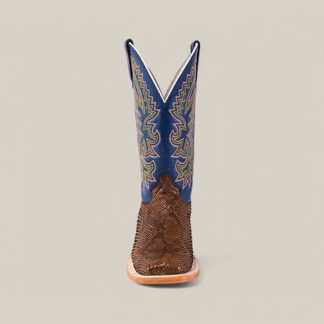 The Exotic Python - Tamarindo - Square Toe boot stands upright against a plain background, featuring a modern square toe design. The textured brown lower contrasts with the blue upper adorned with colorful zigzag stitching, and a light brown sole completes this stylish piece.