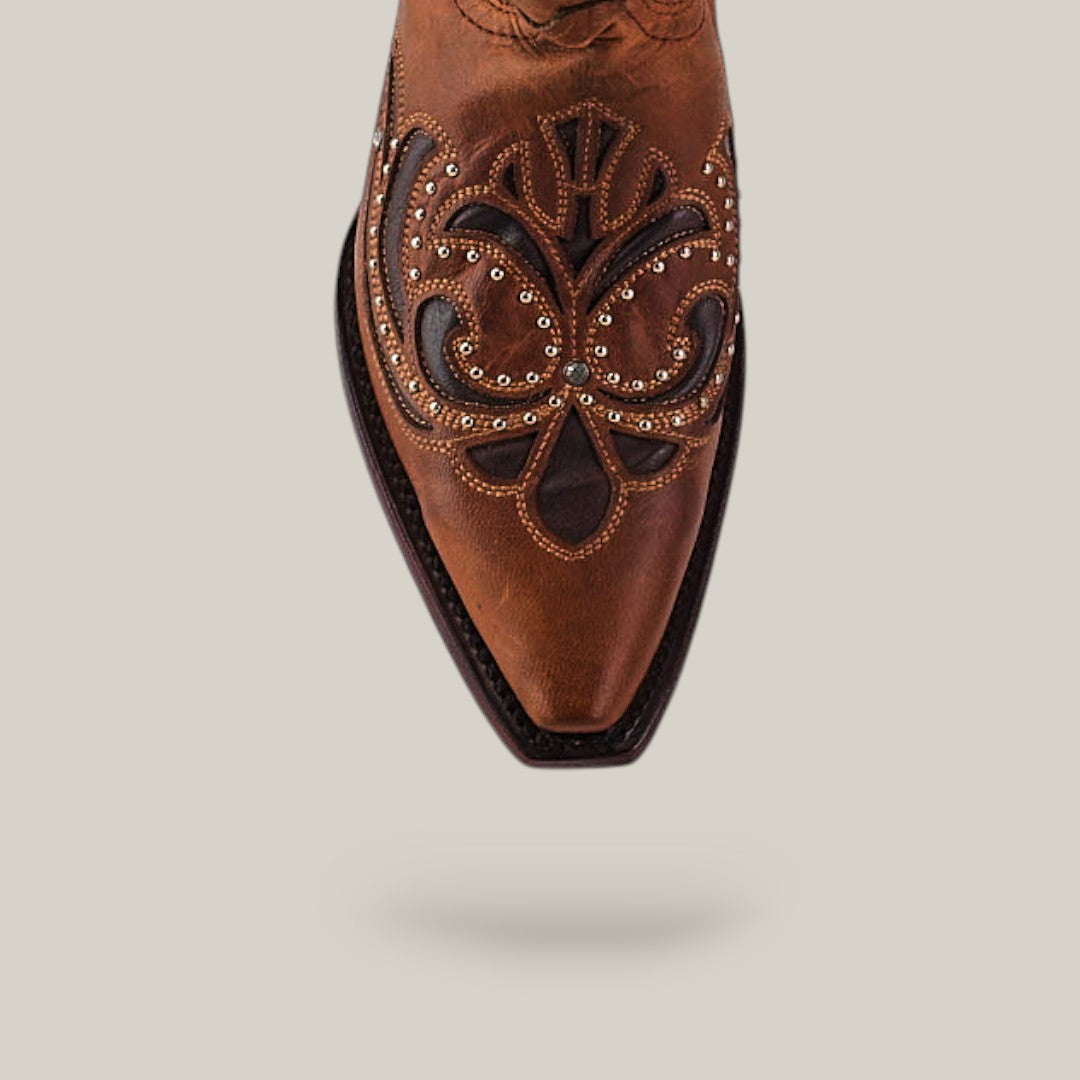 The Dolly - Brown - Snip Toe boot from the Last Call collection, crafted in brown leather with intricate stitching, decorative patterns, and metal studs on the pointed toe, is shown against a light background.