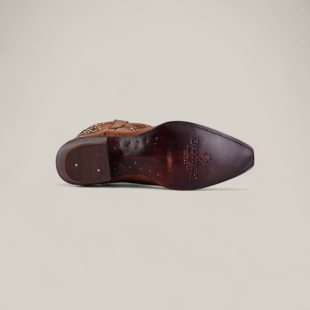 The Dolly - Brown - Snip Toe boot is shown from the bottom, featuring a pointed snip toe, decorative stitching, wooden heel, and visible maker’s logo on the sole against a plain light background.