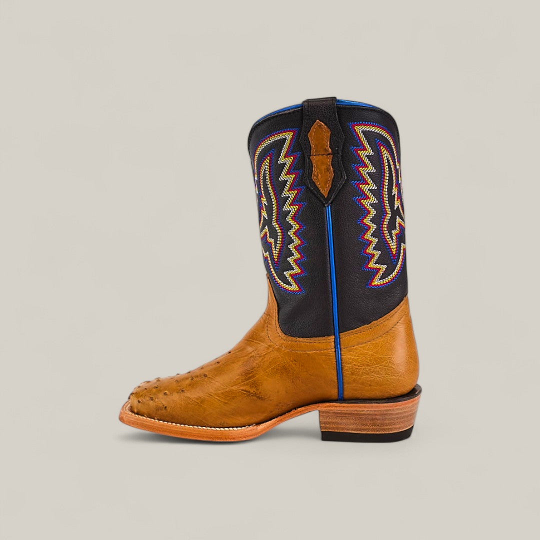 The Exotic Full Quilt Ostrich Fawn Kids Boots feature a brown and black design, colorful embroidery on the shaft, a square toe, and a stacked wooden heel, crafted with Western elegance and shown in side profile against a plain background.