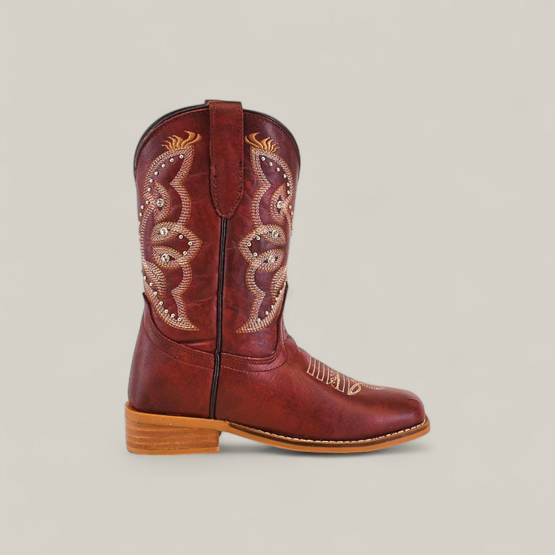 The Blake Cognac - Square Toe Kids Boot is shown in profile against a plain light background, featuring decorative stitching, rich cognac leather, a square toe, and a light wooden heel.