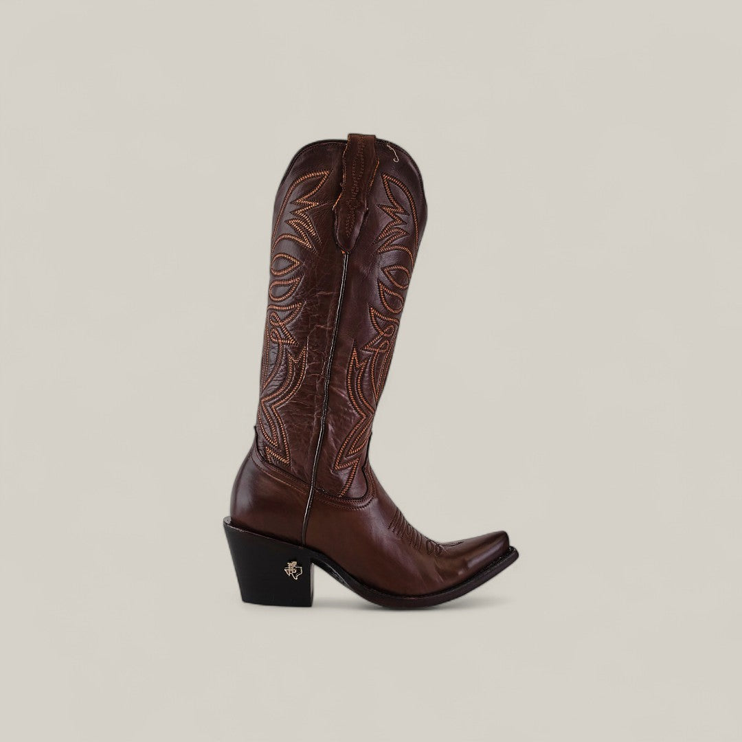 The Kellie Clayton Caramel Leather Sole boot features a tall shaft, snip toe, black angled heel, and intricate stitching. Displayed is a single brown boot against a plain light beige background.