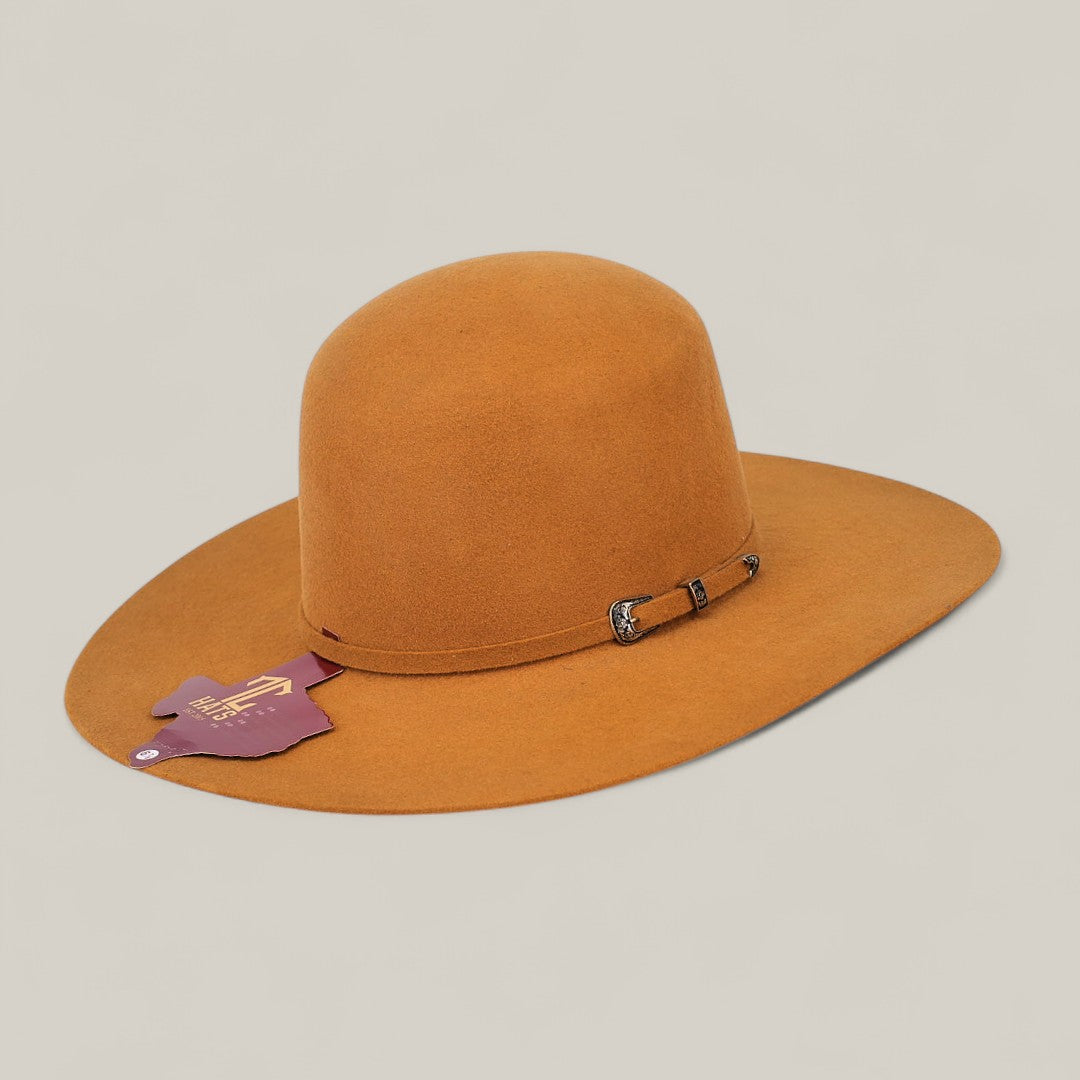 The 4X Caramel - TC Hats is a wide-brimmed, light brown felt Western hat featuring a small side band with buckle and a purple tag with gold lettering attached to the brim. It is shown against a plain, neutral background.