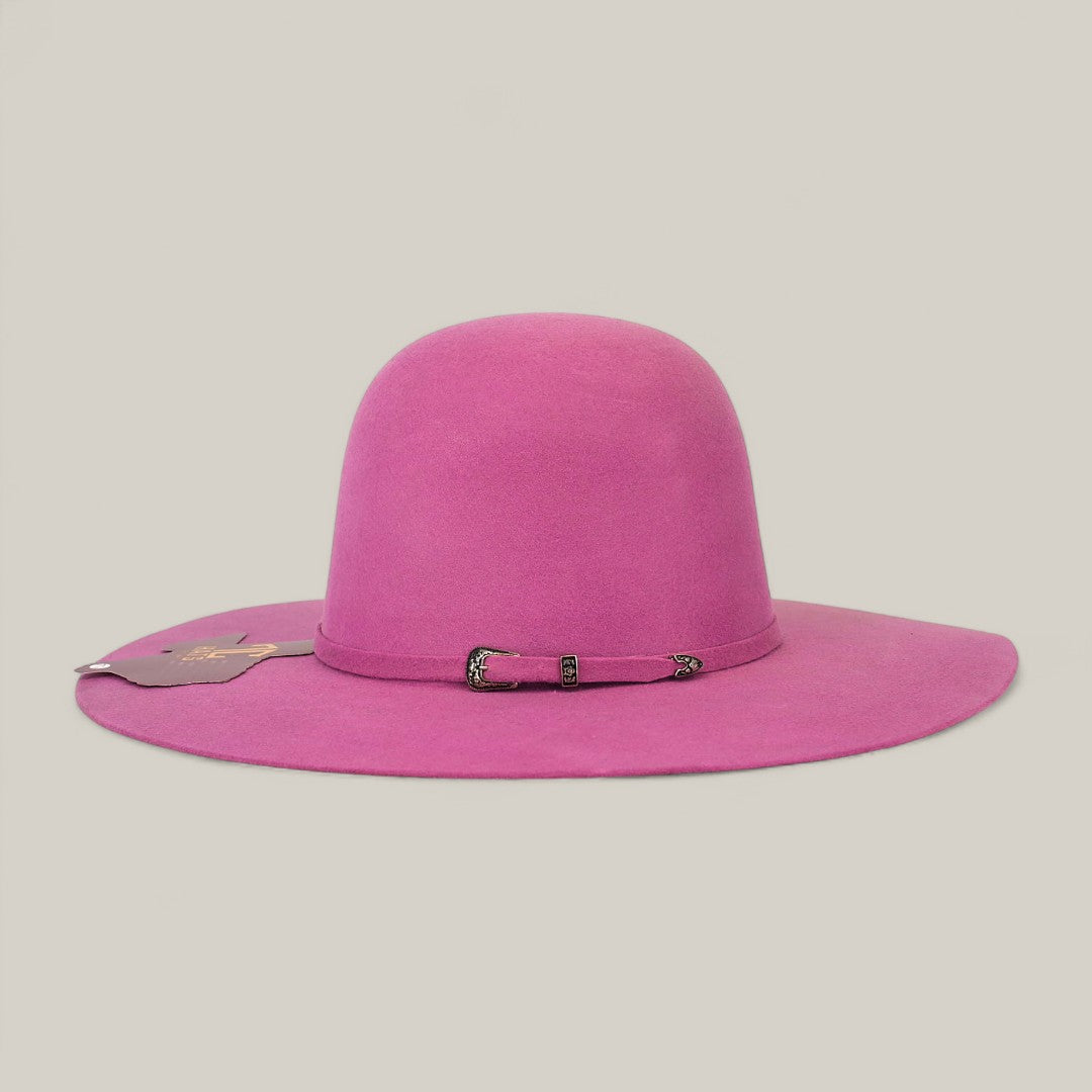 The 4x Pink - TC Hats is a hot pink felt Western hat with a wide brim, open crown Texana style, and a small band at the base. A tag hangs on one side. The background is plain and light-colored.
