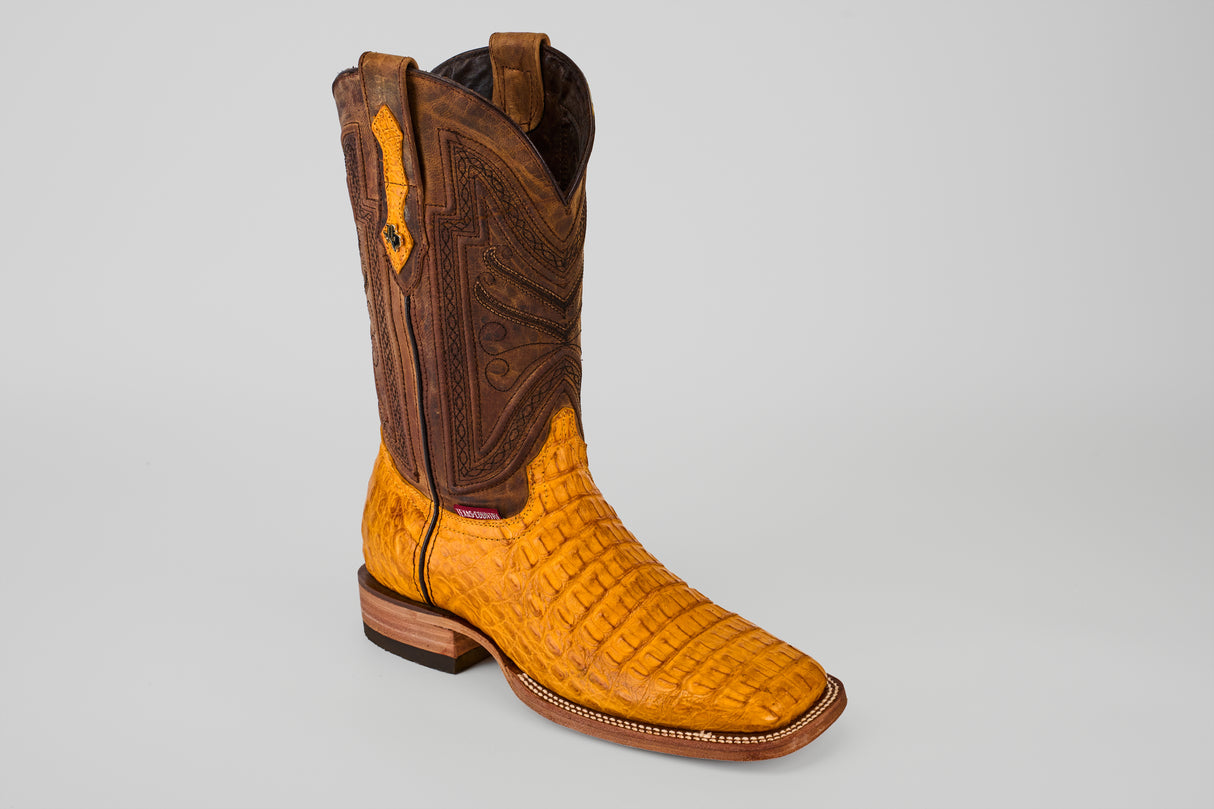 The Exotic Caiman Horn Back - Buttercup- Square Toe boot features a textured yellow caiman leather lower and a tall dark brown upper with decorative stitching, displayed against a plain light gray background.
