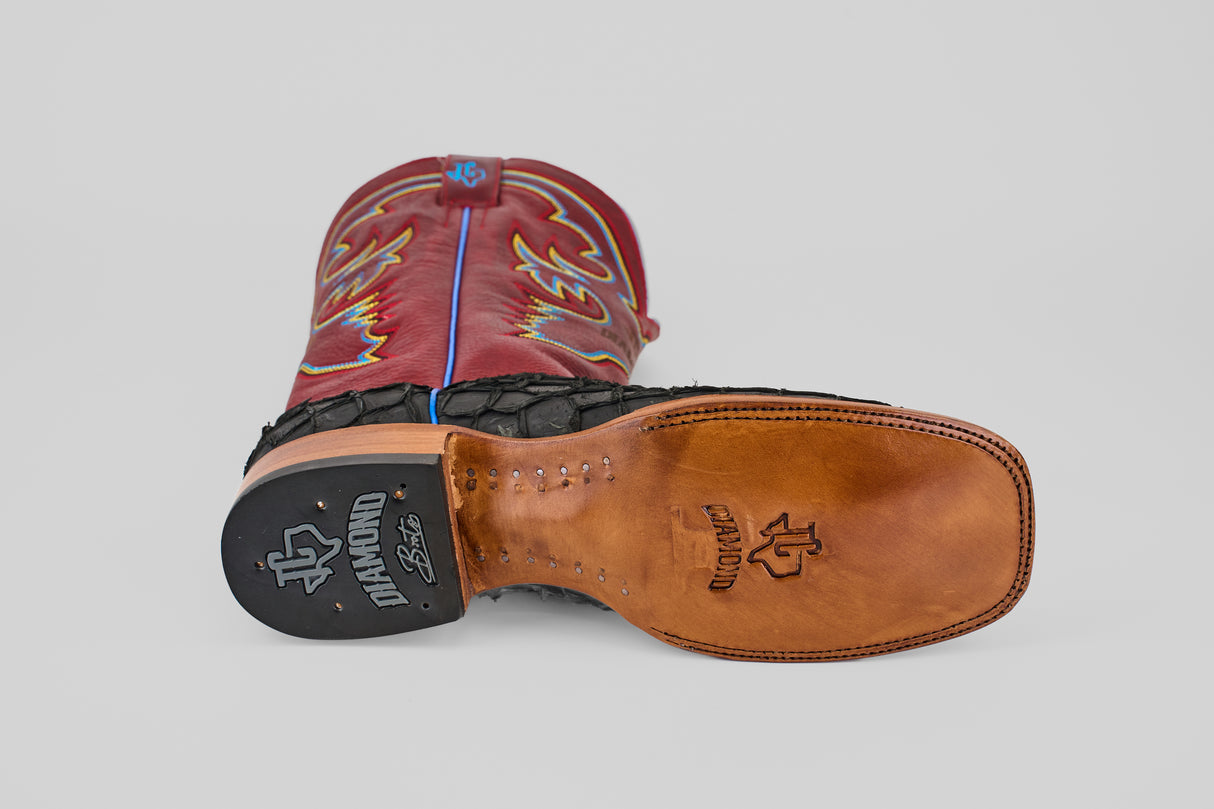 A pair of Dodge - Matte Black - Square Toe boots, one upright and one on its side to display the sole. The matte black boots feature colorful stitching, Pirarucu leather accents, and a leather sole stamped with DIAMOND and the logo.