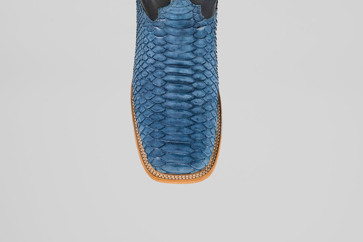 A close-up top view of the Kingsley - Blue Jeans - Square Toe boots reveals blue snakeskin, a square toe, and decorative stitching on a light brown leather sole—men’s boots built for standout style.