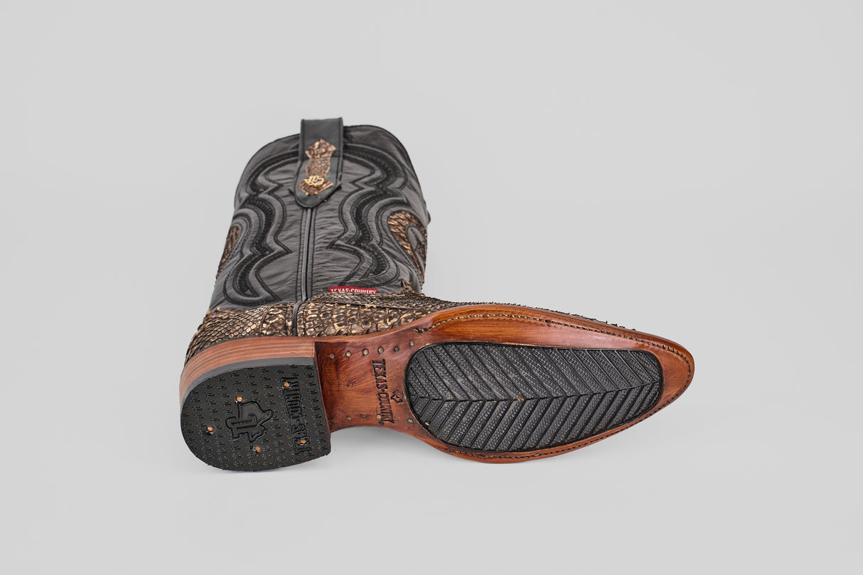 The Tanner – Rustic Bone – Snip Toe cowboy boot is shown from the side and bottom, featuring intricate stitching on black leather, a brown textured lower section, a wooden sole with black rubber grip, and decorative metal accents.