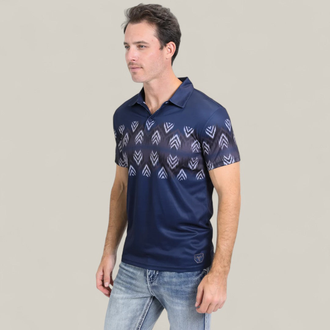A man stands against a plain light background wearing the Mens Performance Fabric Aztec Panoramic Print Navy Polo - PGP10606, featuring a light blue geometric Aztec design, paired with light blue jeans.