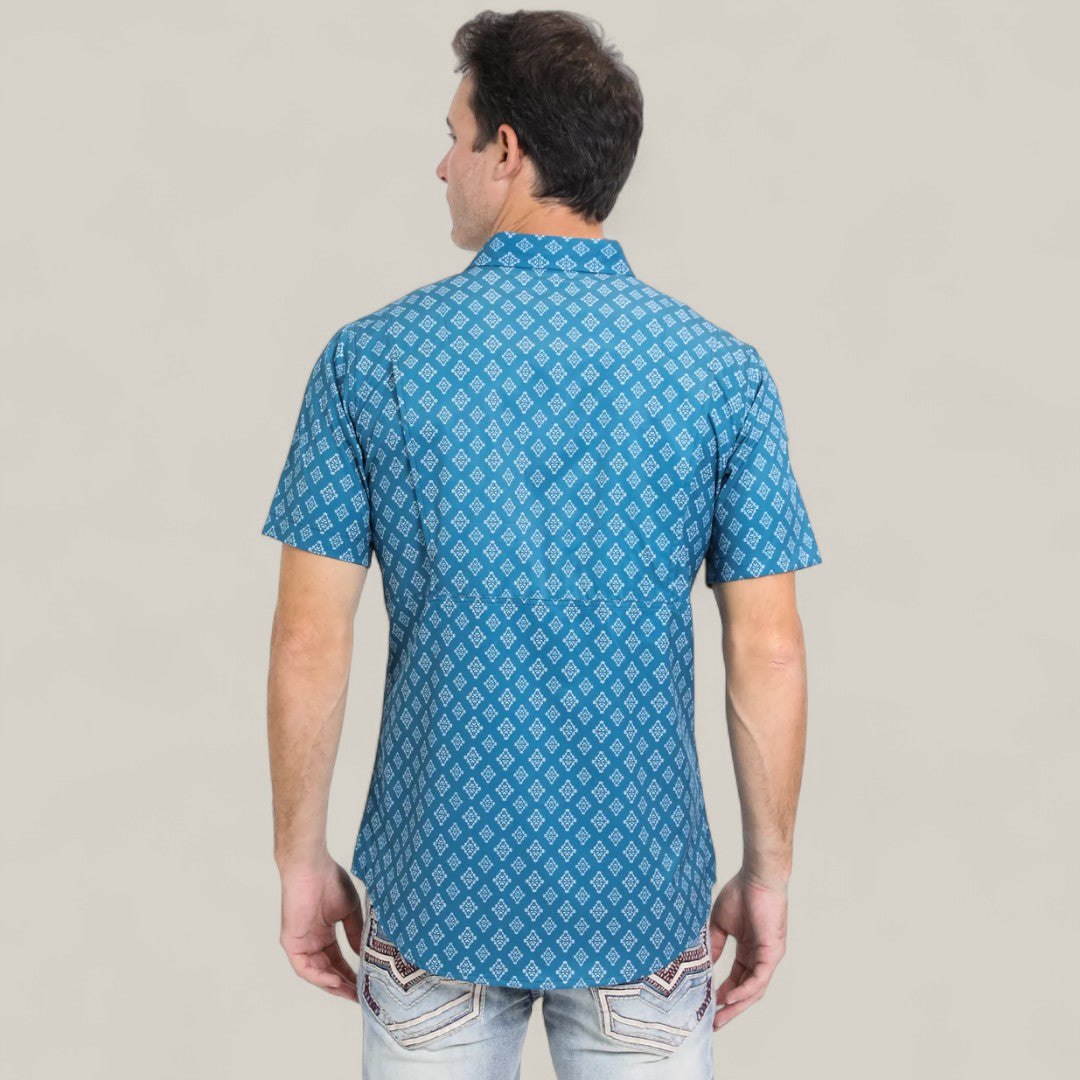 A man stands with his back to the camera, wearing the Mens Performance Western Short Sleeve Aztec Print Blue Shirt (PGW10632) and light jeans with decorative back pocket stitching, set against a plain light gray background.