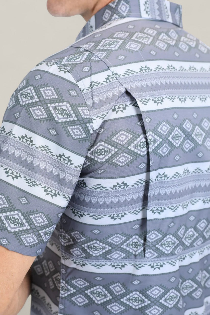 A close-up of the Mens Performance Western Short Sleeve Aztec Print Grey Shirt (PGW10649) highlights its geometric diamond pattern in grey, white, and green, plus a hidden zippered side vent for comfort.