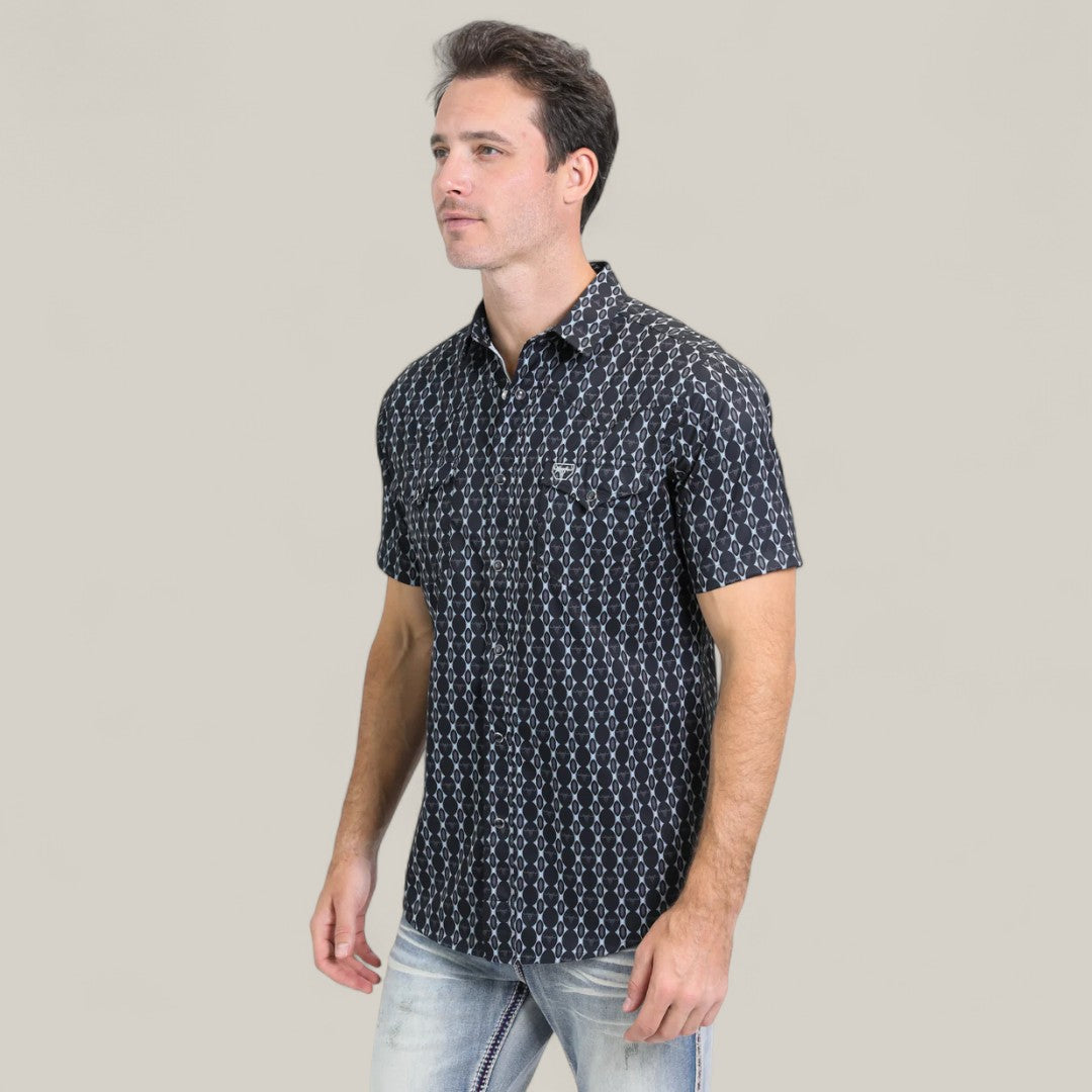 A man wearing the Mens Performance Western Short Sleeve Aztec Print Navy Shirt (PGW10646) and light blue jeans stands against a plain, light beige background.
