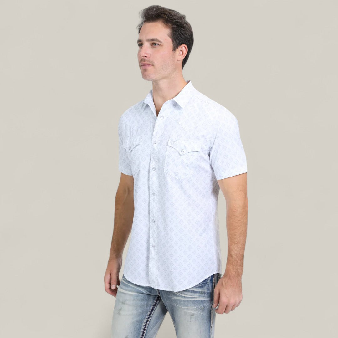A man wearing a white Men’s Performance Western Short Sleeve Aztec Print Shirt (PGW10631) and faded blue jeans stands against a plain beige background.