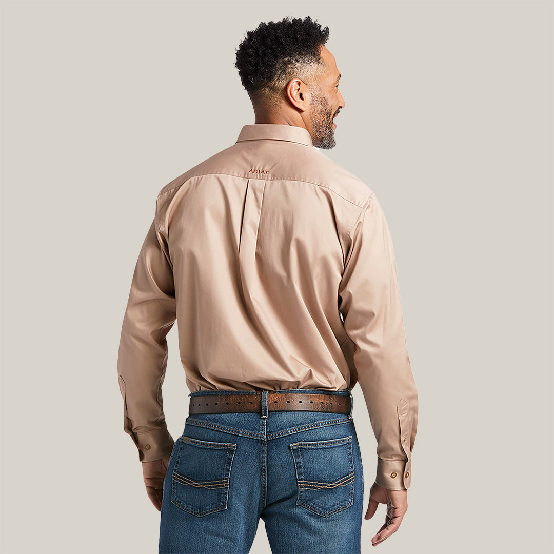 A man with short curly hair stands back to the camera in a Solid Twill Classic Fit Shirt Kaki (10000505) and blue jeans, hand on hip highlighting his brown leather belt. The plain white background enhances the premium cotton twill texture.