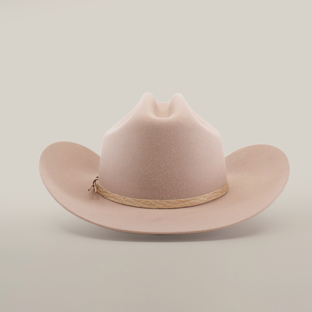 The 6X Country Belly, a beige cowboy hat made from premium sheep wool, features a wide brim and crown crease on a white backdrop. A light brown braided band adds rustic charm to this classic felt hat.