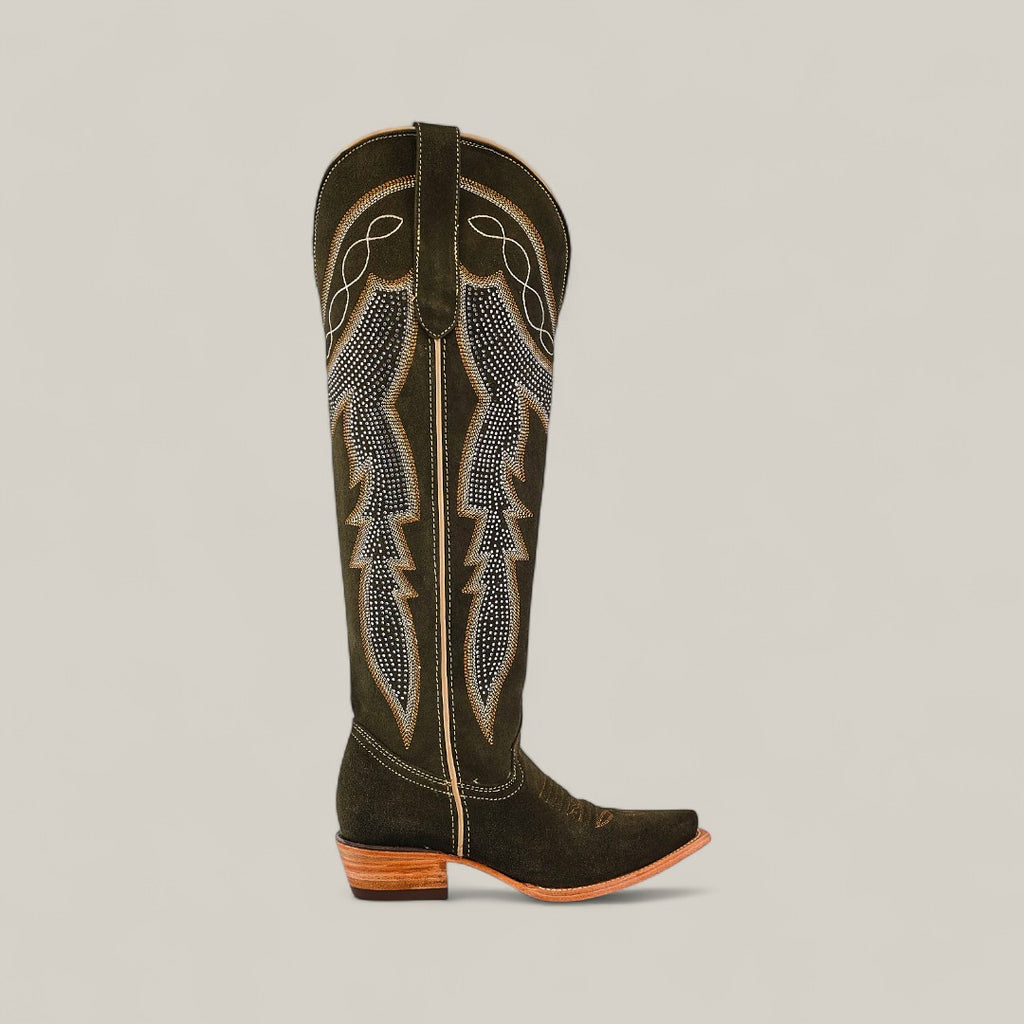 The Della Olive Green boot features a tall shaft, snip toe, decorative stitching on olive green leather, and a low wooden heel, shown against a plain beige background.