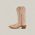 The Tessa Champagne Mid Shaft Snip Toe boot features light beige color, decorative stitching, a wooden stacked heel, and a pull tab—shown in profile against a light background—for women who value style and comfort.