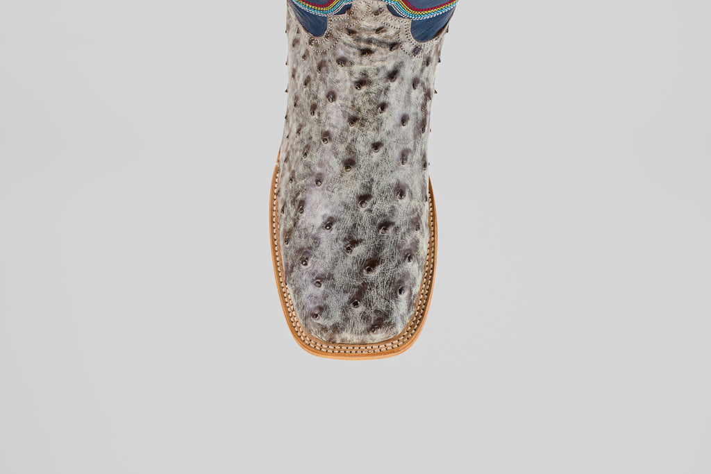 A top-down view of the Russell - Rustic Gray - Square Toe boot, featuring a textured, spotted gray surface, square toe, and tan stitching.
