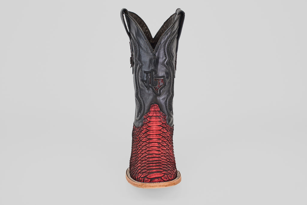 The Tanner – Scarlet – Square Toe is a western cowboy boot with a black upper and red python leather lower, detailed stitching, light brown sole, and square toe, shown from the front against a plain background.