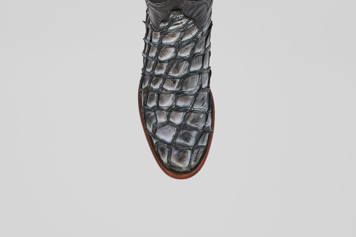 A close-up, top view of the Conor - Newspaper - Roper Toe boot showcases its textured, scale-like pattern and brown sole against a white background—a striking example of exotic leather craftsmanship.