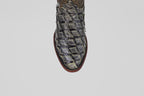 Close-up of the Conor - Charcoal - Roper Toe boot's textured, dark charcoal toe with a square pattern, possibly crafted from exotic fish leather, shown against a plain light gray background.