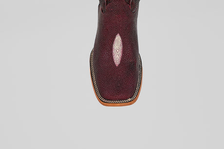 A close-up, top view of the Ranger – Wine – Square Toe boot shows textured, shiny maroon stingray leather and light brown welt stitching around the sole, set against a plain gray background.
