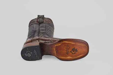The Tanner Platinum - Dune - Square Toe (Imperial) cowboy boot is shown on its side, highlighting the branded sole and heel, textured leather, decorative stitching, and a mix of dark and light brown shades.