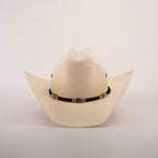 The 500X Country Straw Hat features a plain white design with a wide brim, crafted from premium materials, and adorned with a black band featuring ornate gold accents.