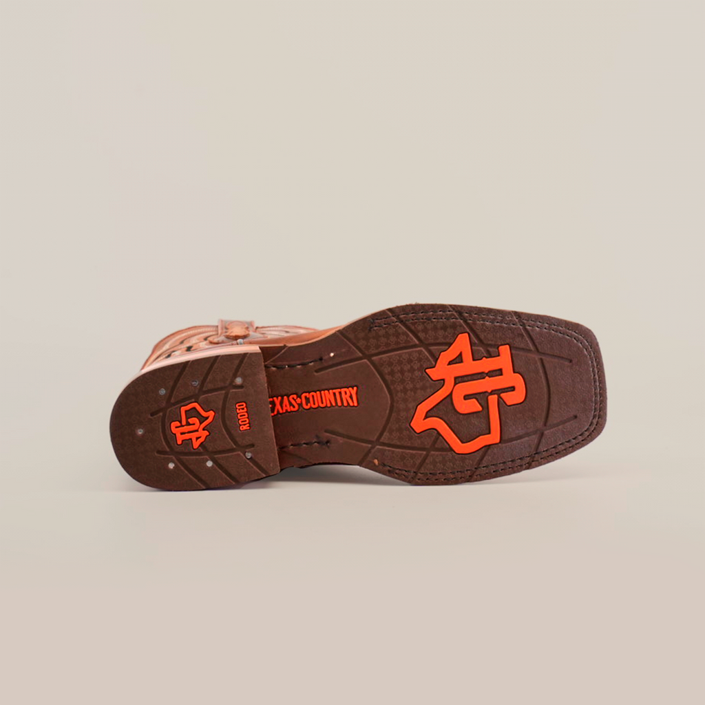 The Fresno Shedron boots display a brown cowboy boot sole with a red Texas Country logo and distinct tread pattern. Crafted from premium cowhide leather, they feature a slip-resistant sole, shown on its side against a plain white background to highlight the design.