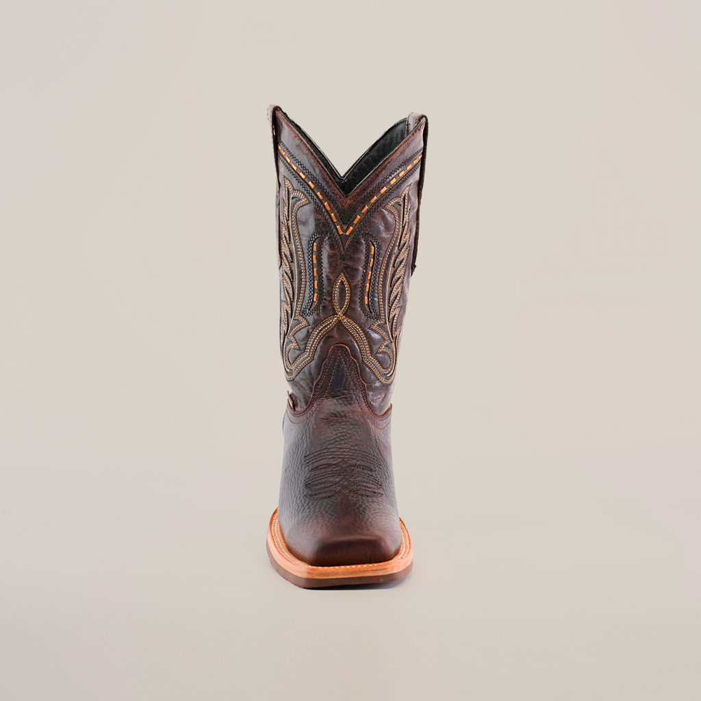 The Cheyenne Chocolate boot, featuring a rodeo toe and intricate stitching, is crafted from premium cowhide for a slightly worn look. Displayed on a white backdrop, it merges style with functionality thanks to its slip-resistant sole.