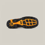 The image displays the sole of the Amazonas Honey Composite Toe - E6002, resembling Texas Country Work Boots with a black and orange rugged tread pattern. A central logo emphasizes its durability on various terrains, set against a plain light beige background.